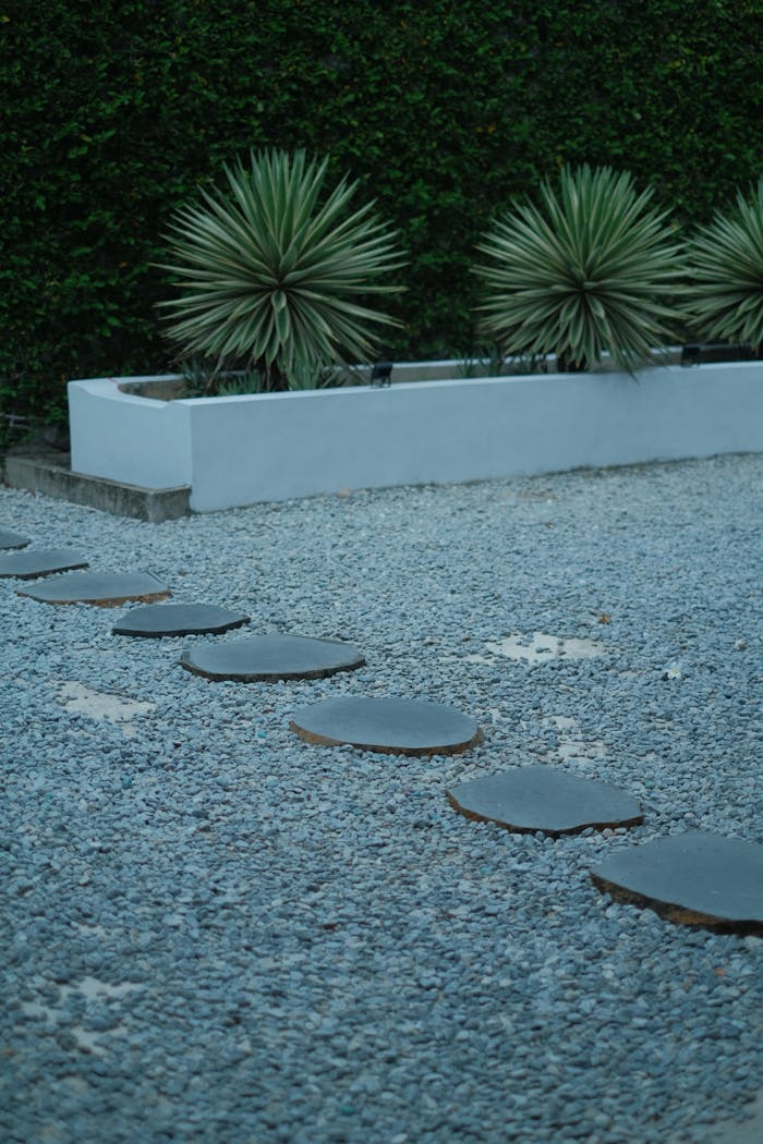 services-04 Circular stone pathway in a modern garden with agave plants and gravel.